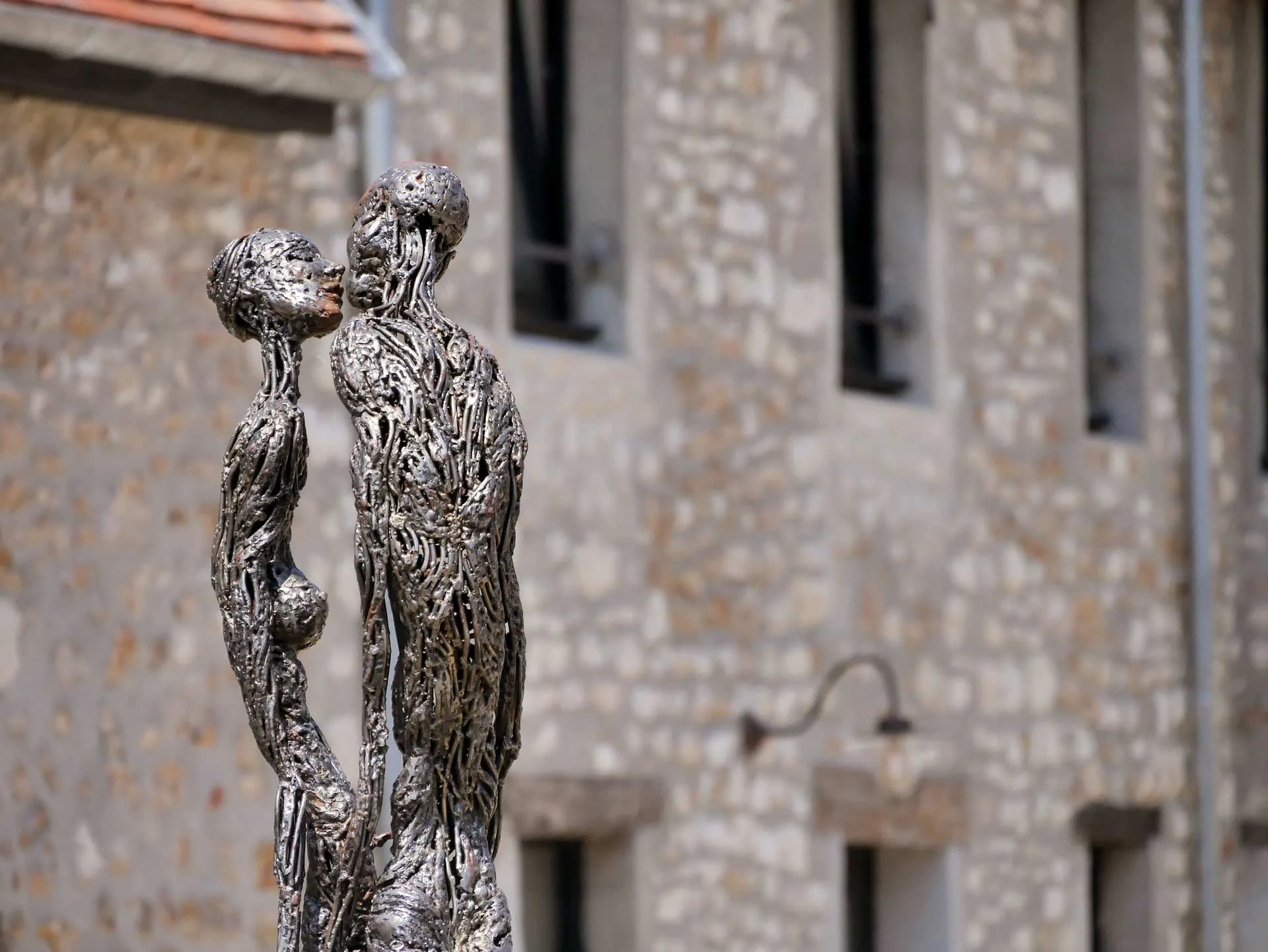 Sculpture contemporaine représentant deux figures humaines abstraites face à face, devant la façade de la maison d'hôtes Val Trebbia